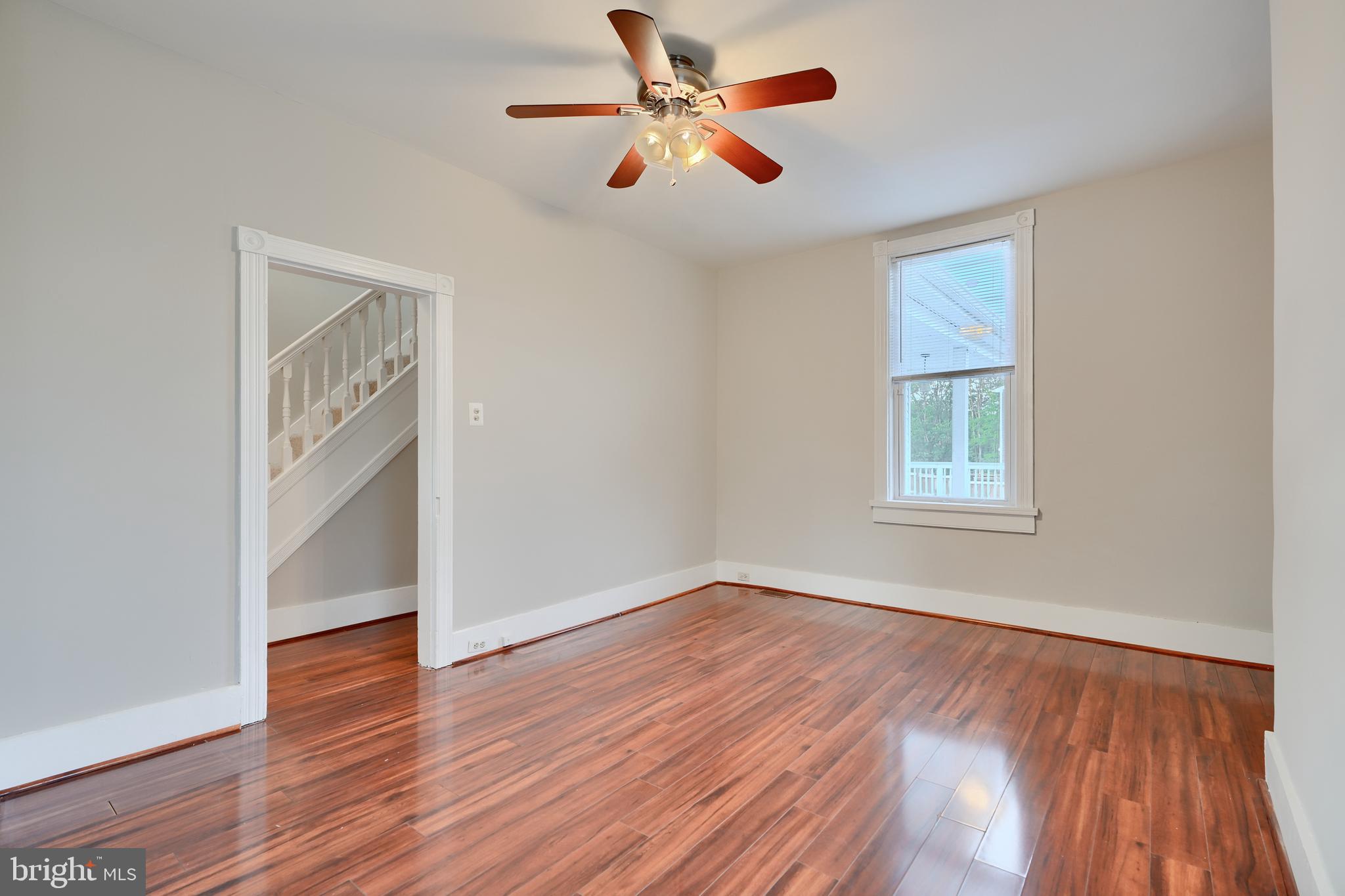 1817 Summit Avenue Baltimore, MD 21227 - Photo 7 of 28 an empty room with wooden floor chandelier fan and windows