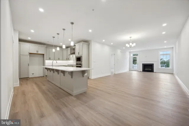 a large kitchen with a large counter top stainless steel appliances and wooden floor