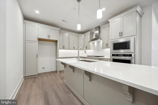 a kitchen with stainless steel appliances a stove refrigerator a sink and a oven with wooden floor