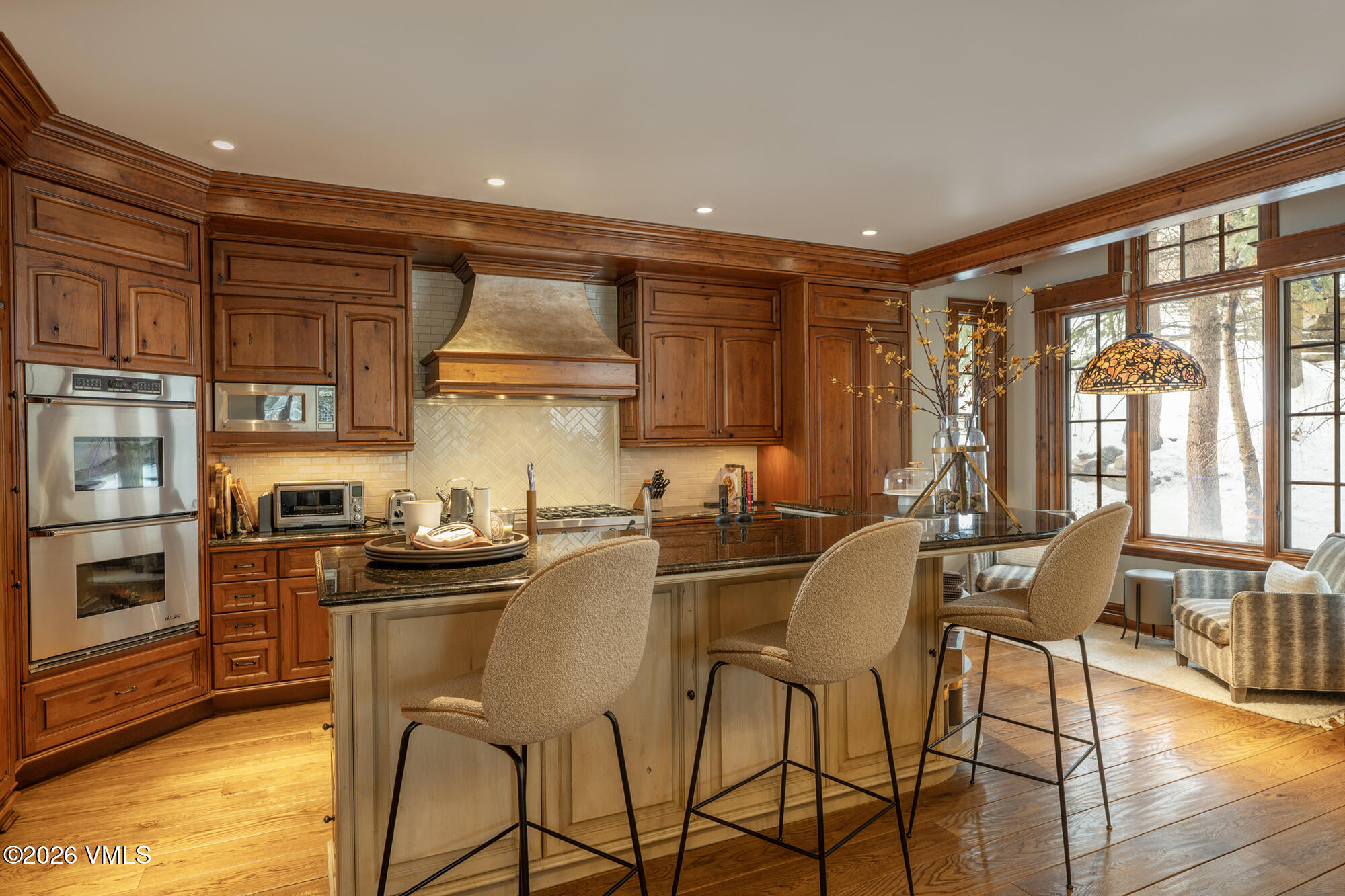 325 West Forest Road Vail, CO 81657 - Photo 5 of 33 a kitchen with stainless steel appliances granite countertop a stove top oven a sink a dining table and chairs with wooden floor