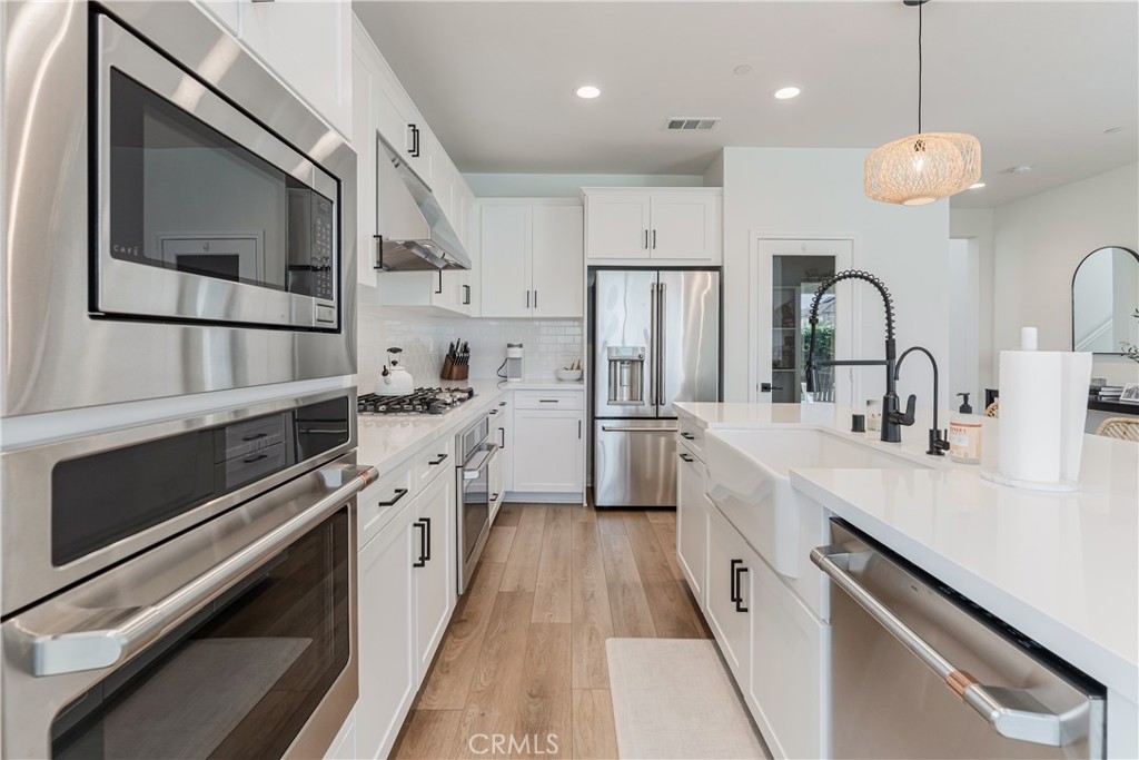 32067 Dawning Ridge Temecula, CA 92591 - Photo 11 of 73 a kitchen with stainless steel appliances a sink cabinets and a wooden floor