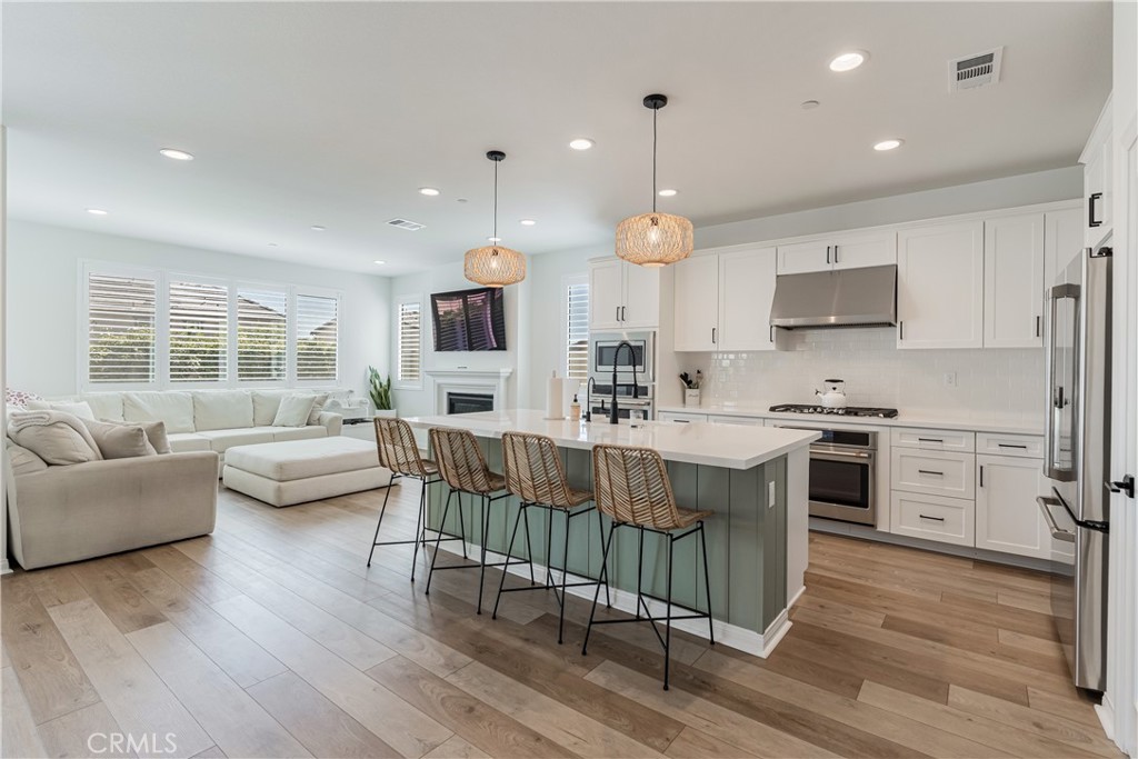 32067 Dawning Ridge Temecula, CA 92591 - Photo 3 of 73 a kitchen with stainless steel appliances granite countertop a stove a sink dishwasher a microwave oven and a dining table with wooden floor