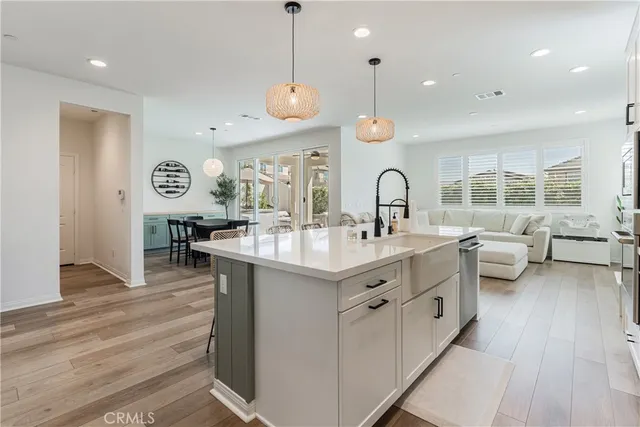 a kitchen with stainless steel appliances a dining table chairs and wooden floor