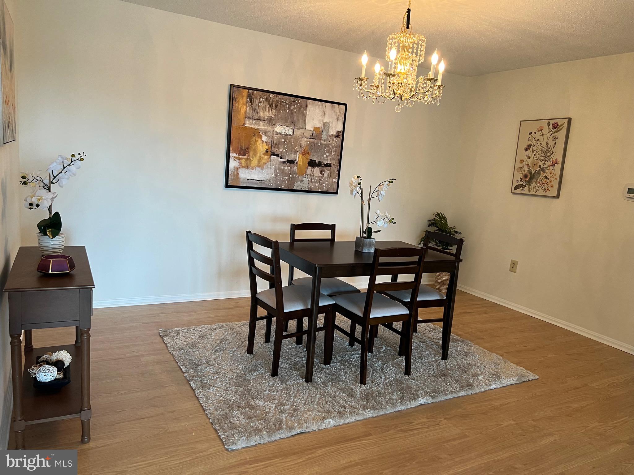 15100 Interlachen Drive, Unit 4709 Silver Spring, MD 20906 - Photo 5 of 22 a dining room with wooden floor a chandelier a wooden table and chairs