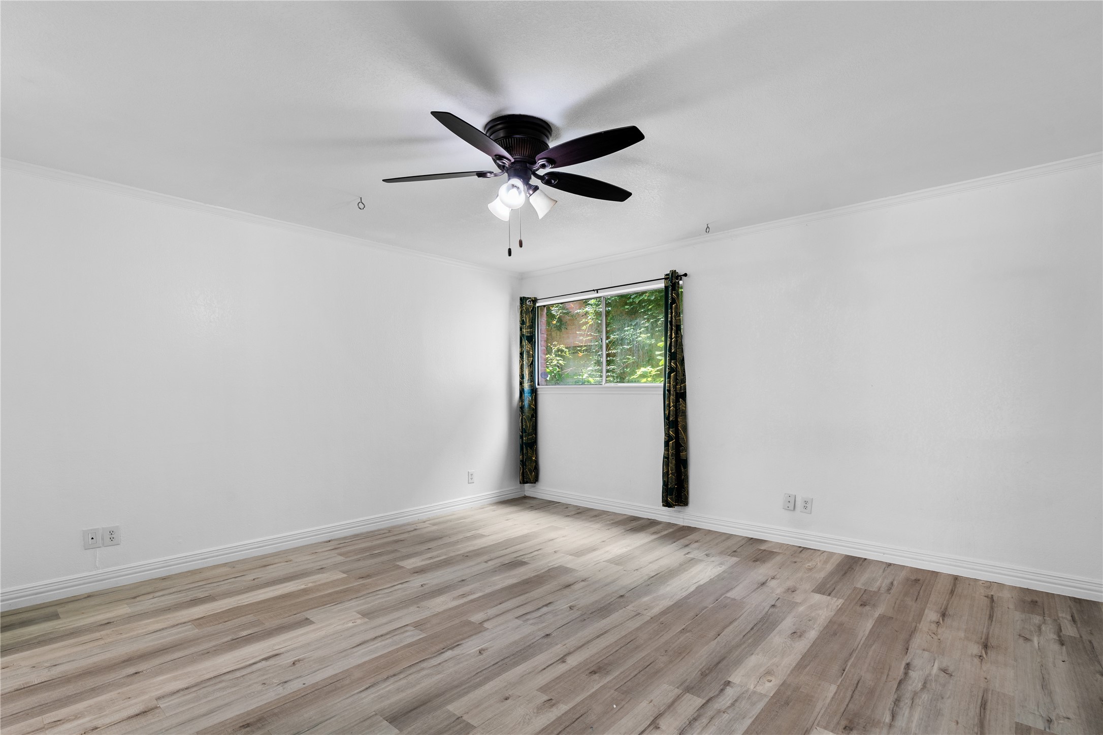 6303 Crab Orchard Road, Unit 3 Houston, TX 77057 - Photo 16 of 30 Escape to a bedroom designed for total relaxation. The oversized window offers a peaceful view of the backyard greenery, while the dark-wood ceiling fan provides a sophisticated contrast against the gallery-white walls. The spacious layout easily accommodates a king-sized suite.