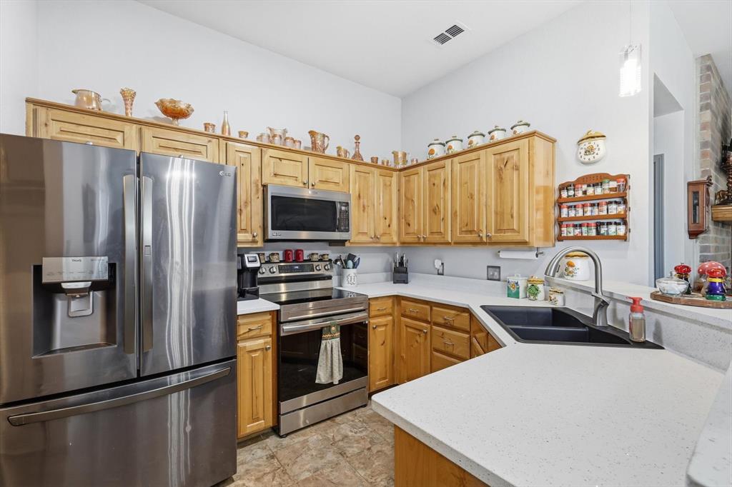 11649 Mitchell Circle Ponder, TX 76259 - Photo 6 of 38 a kitchen with stainless steel appliances a sink a stove a refrigerator cabinets and a counter top space