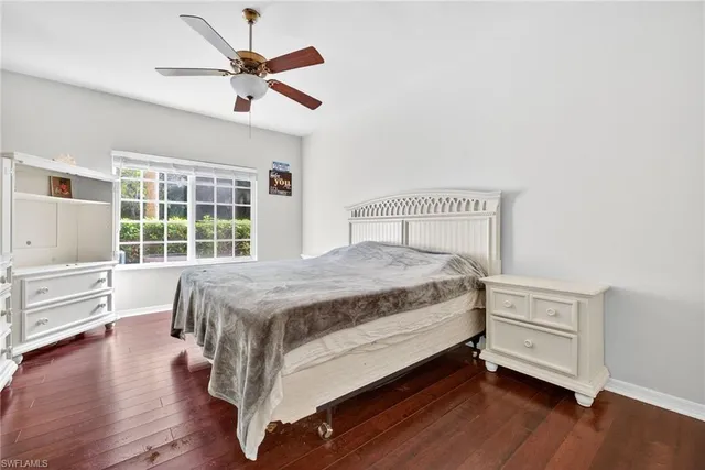 a bedroom with a bed and a large window with wooden floor