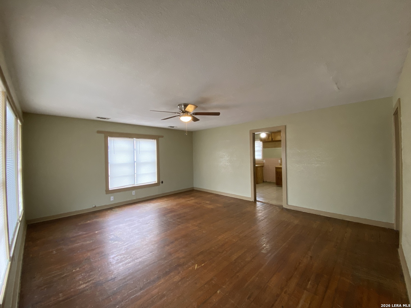116 Tagert Street Pleasanton, TX 78064 - Photo 2 of 6 an empty room with wooden floor chandelier fan and windows