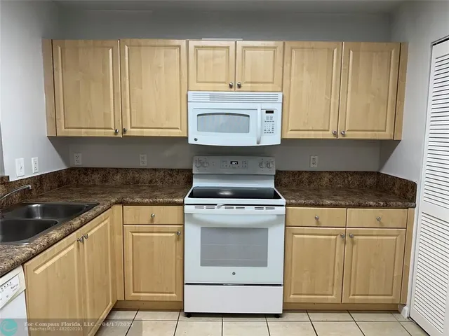 a kitchen with granite countertop white cabinets and white appliances