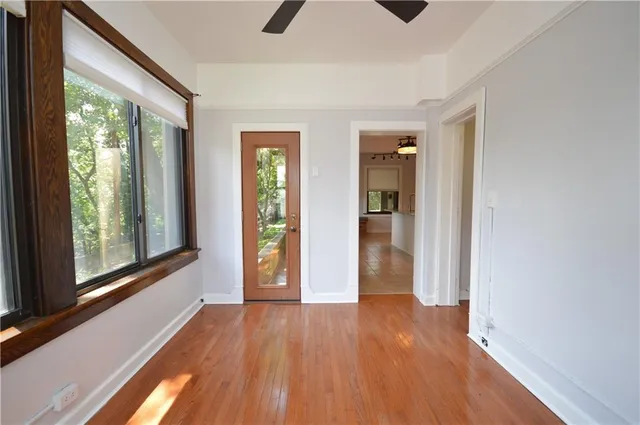 a view of an empty room with wooden floor and a window