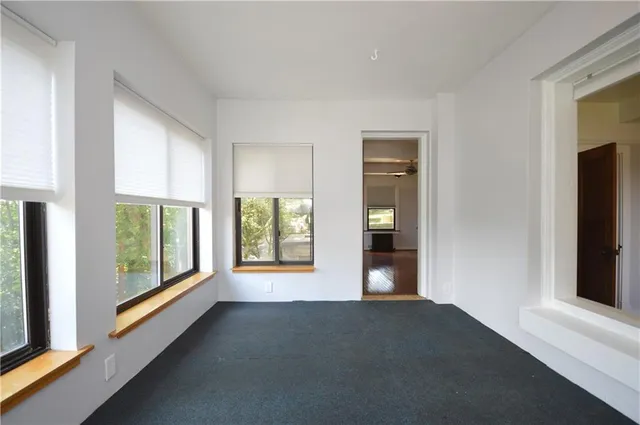 a view of an empty room with a window and fire place