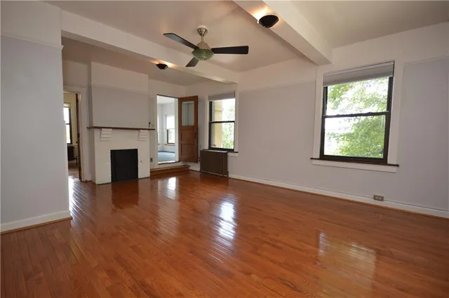 a view of an empty room with wooden floor and a window