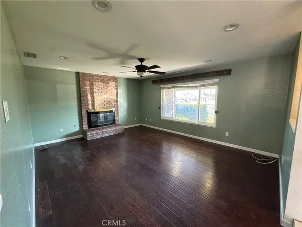 an empty room with wooden floor fireplace and windows
