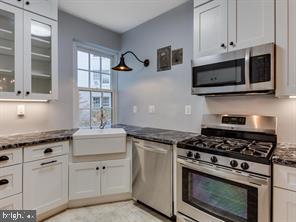 2737 Devonshire Place Northwest, Unit 129 Washington, DC 20008 - Photo 8 of 30 a kitchen with stainless steel appliances white cabinets and a stove a oven with wooden floors