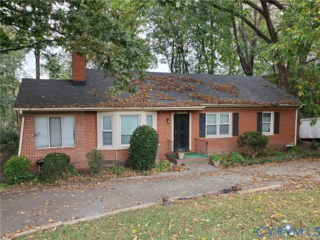View of front facade with brick siding, a chimney,