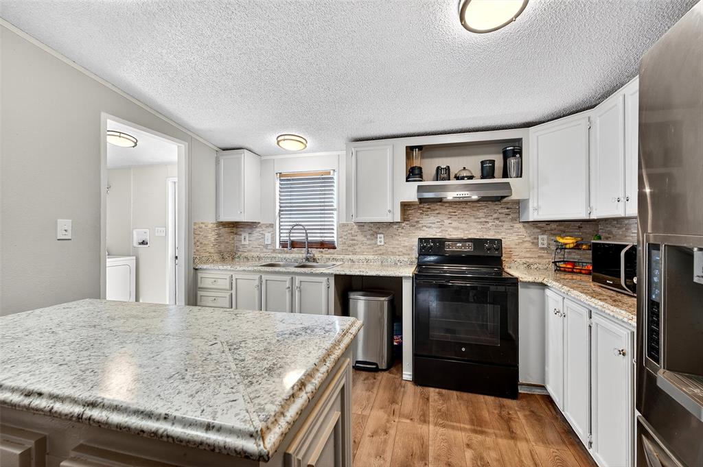 1918 East Foster Crossing Road Anna, TX 75409 - Photo 19 of 27 a kitchen with stainless steel appliances granite countertop a stove top oven a sink dishwasher and a refrigerator with wooden cabinets
