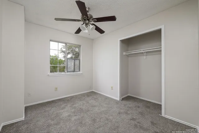 an empty room with windows and fan