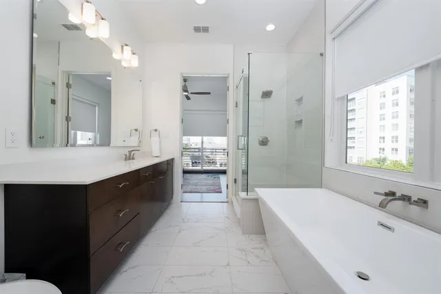 a spacious bathroom with a tub sink shower and mirror