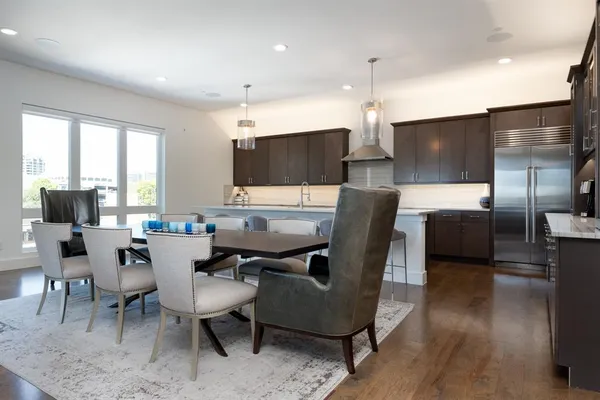 a living room with couches and kitchen view with wooden floor
