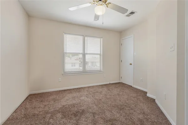 an empty room with a chandelier fan and windows