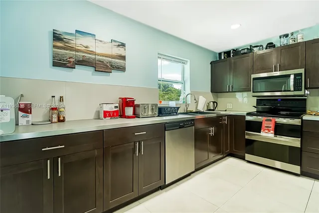 a kitchen with kitchen island stainless steel appliances a sink cabinets and a window