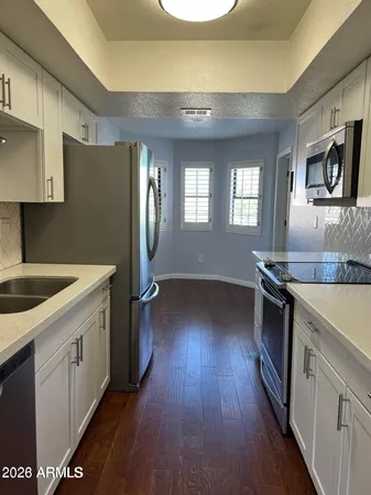 a kitchen with a sink wooden floor and stainless steel appliances