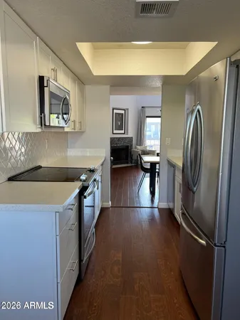 a kitchen with stainless steel appliances granite countertop a refrigerator a stove and a sink with wooden floor