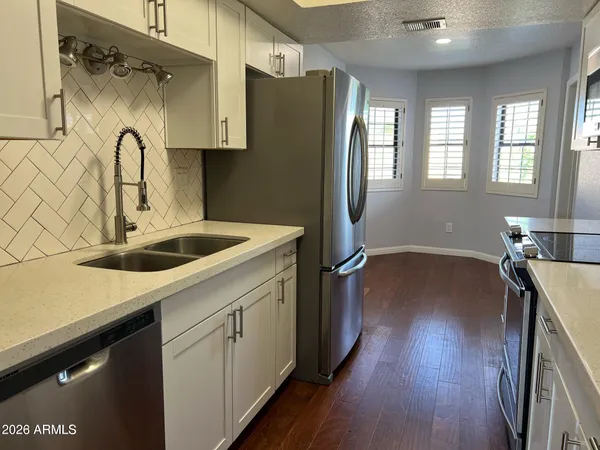 a kitchen with stainless steel appliances a refrigerator sink and wooden floor