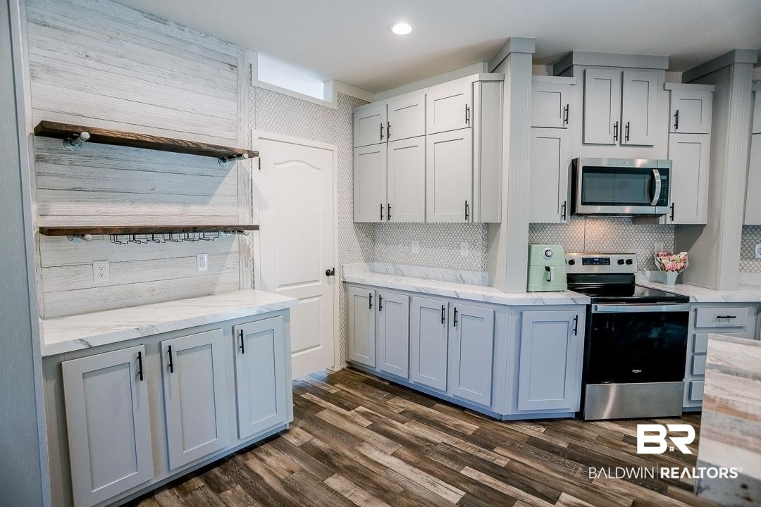 19180 Horseshoe Circle Seminole, AL 36574 - Photo 11 of 38 Kitchen with open shelves, appliances with stainless steel finishes, dark wood finished floors, backsplash, and light stone counters