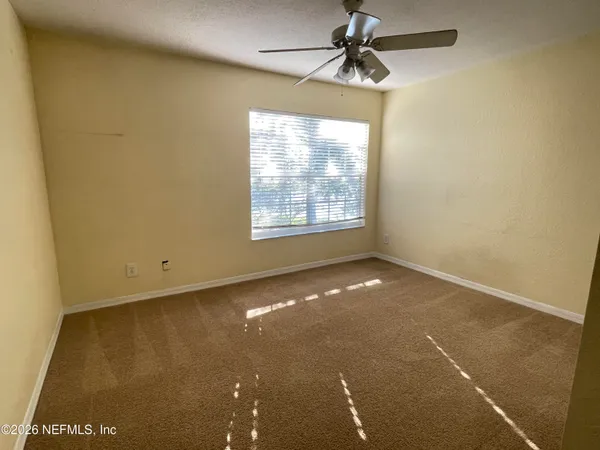 an empty room with a window and a ceiling fan