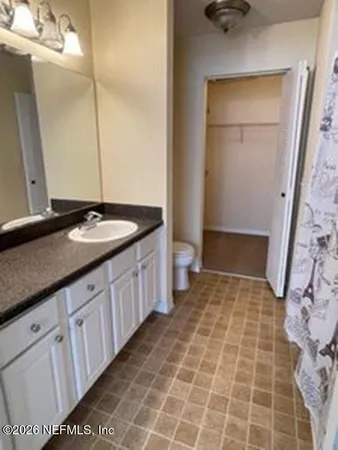 a bathroom with a granite countertop sink a toilet and a mirror