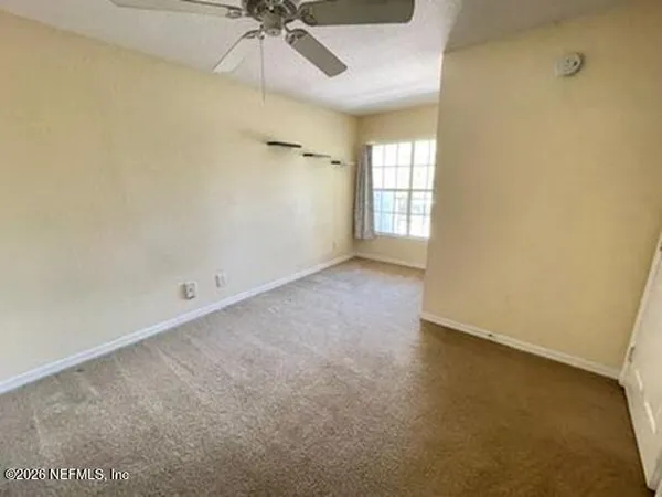 en empty room with windows and ceiling fan