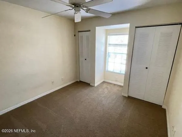 an empty room with a window and a fan