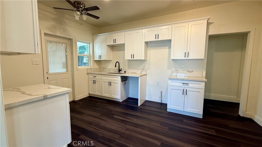 4542 Bandini Avenue Riverside, CA 92506 - Photo 9 of 22 a kitchen with a sink dishwasher a stove and white cabinets with wooden floor