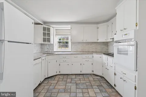 a kitchen with granite countertop white cabinets and white appliances