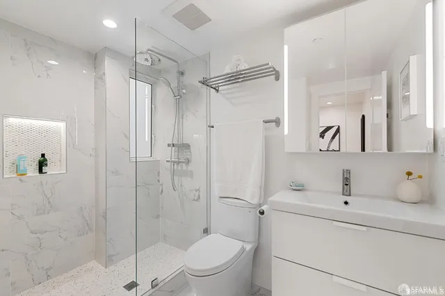 a bathroom with a shower sink vanity mirror and toilet