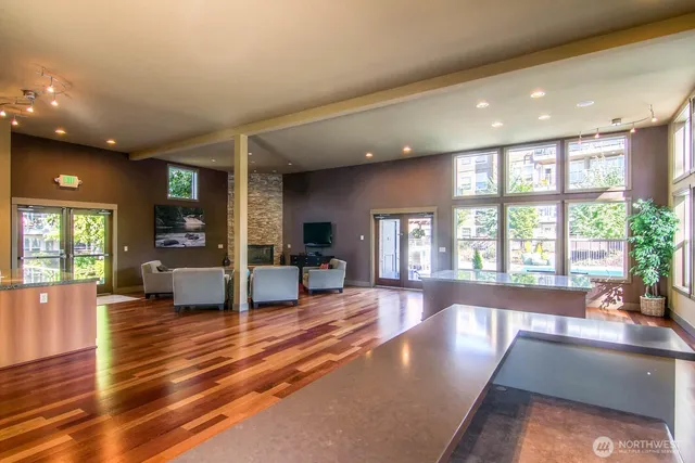 a large living room with stainless steel appliances furniture large windows and a kitchen view