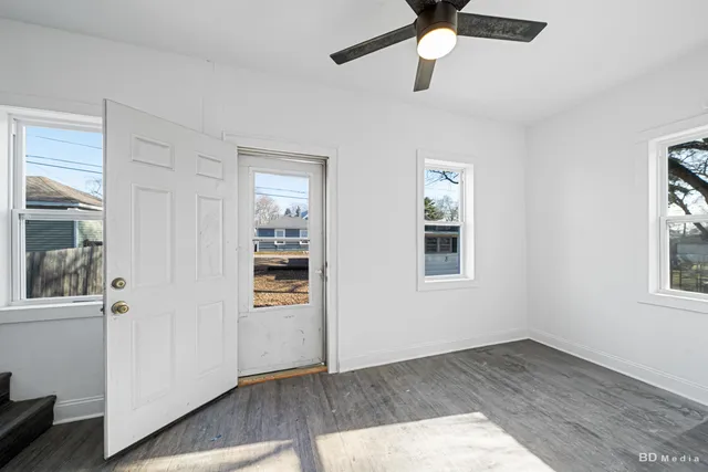 a view of an empty room with a window and wooden floor