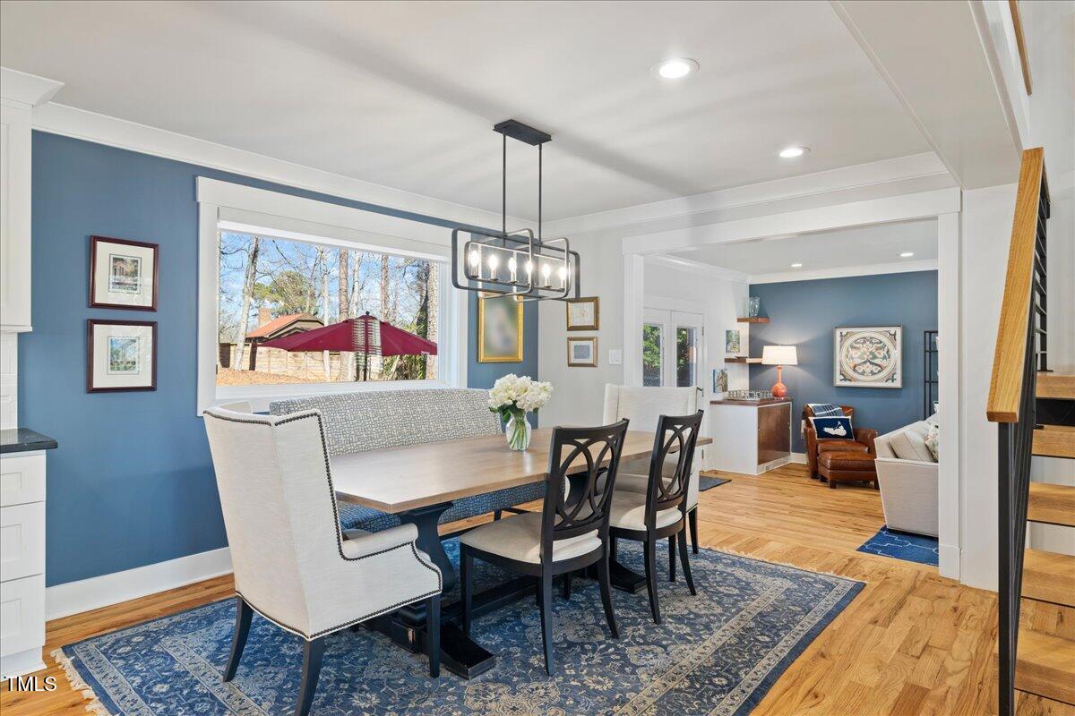 2605 Ridge Road Raleigh, NC 27612 - Photo 7 of 51 a dining room with wooden floor a chandelier a wooden table and chairs