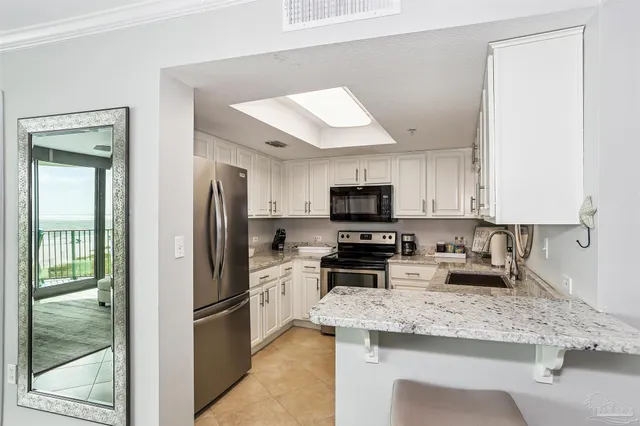 a kitchen with granite countertop a sink stainless steel appliances and white cabinets