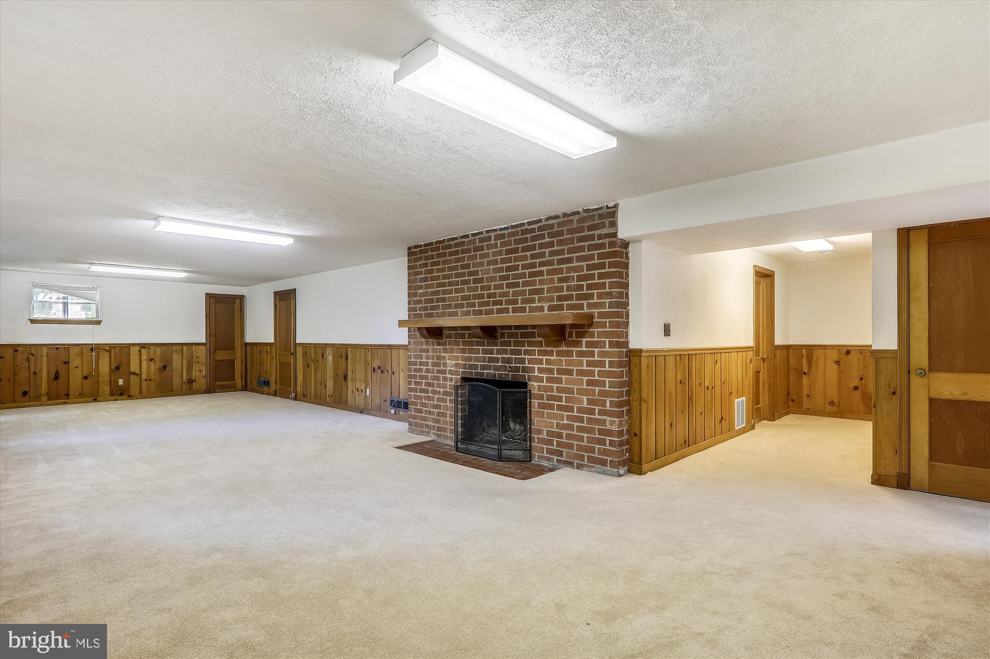 3303 Winnett Road Chevy Chase, MD 20815 - Photo 30 of 54 an empty room with a fireplace and chandelier fan