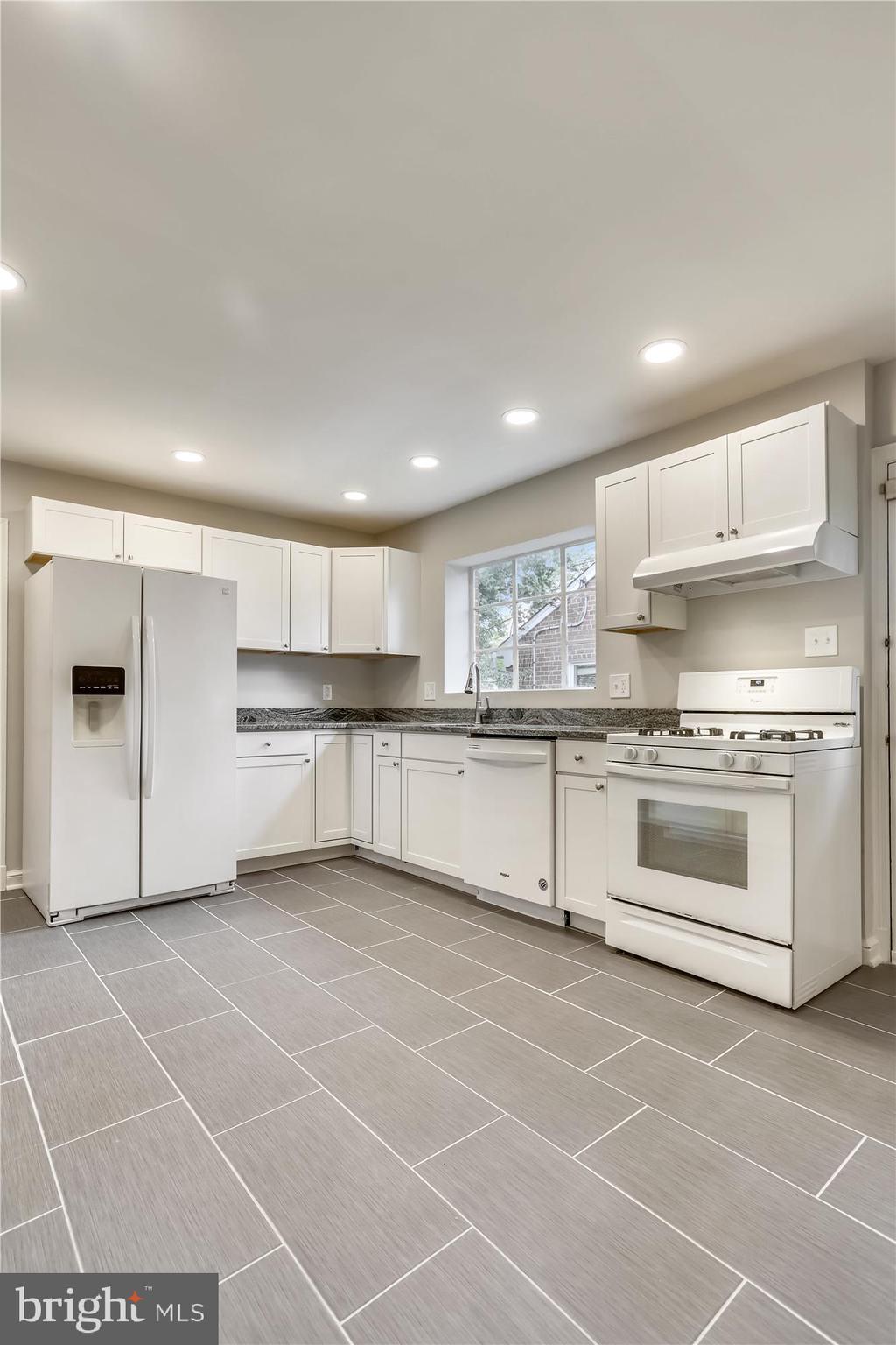 3303 Winnett Road Chevy Chase, MD 20815 - Photo 6 of 54 a large white kitchen with kitchen island a stove a sink and a refrigerator