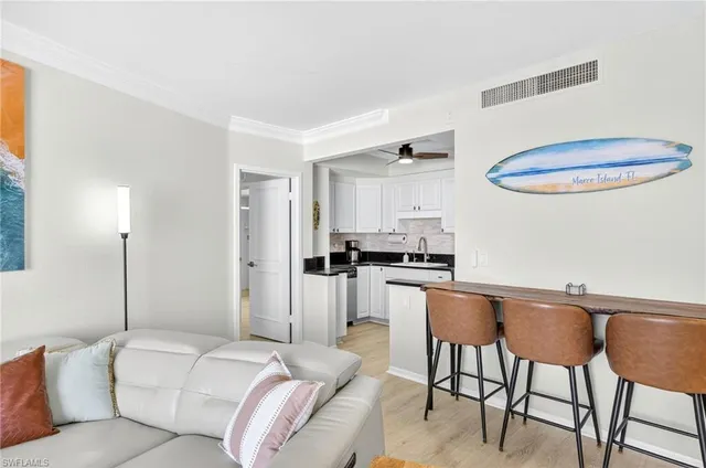 a living room with stainless steel appliances furniture a refrigerator and a dining table