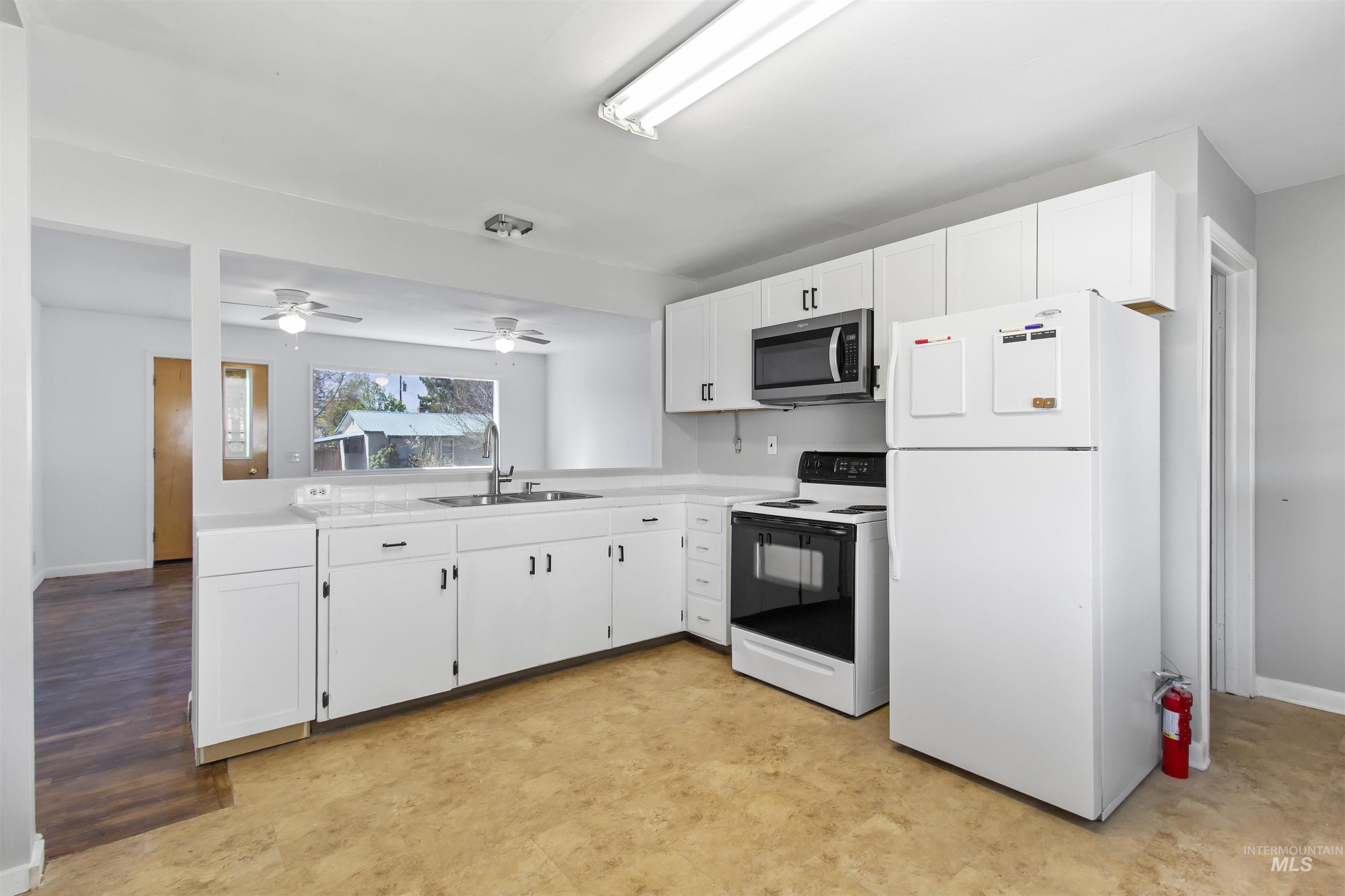 412 Madison Street Twin Falls, ID 83301 - Photo 6 of 42 Kitchen with white appliances, white cabinetry, light countertops, and a ceiling fan