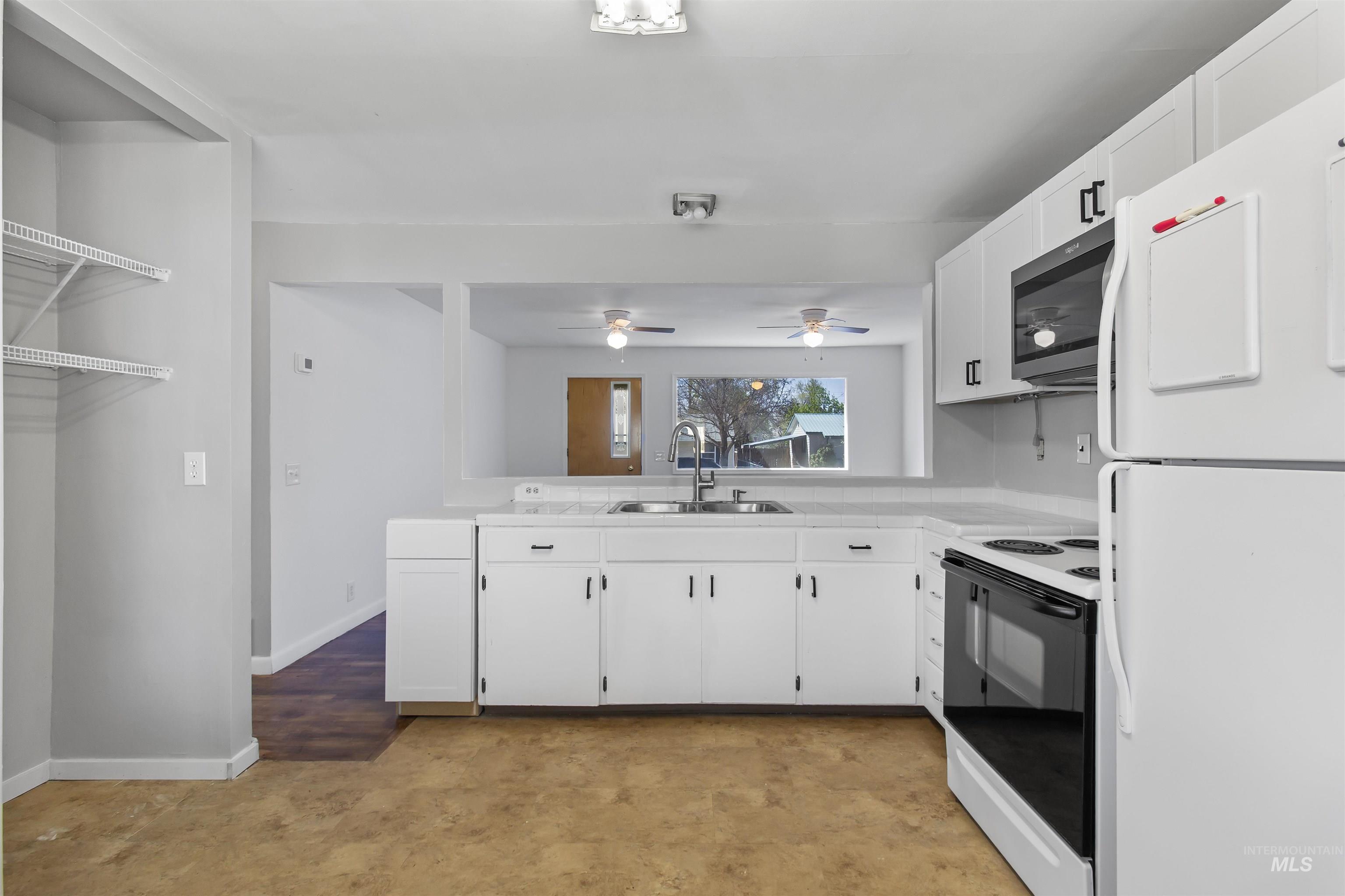 412 Madison Street Twin Falls, ID 83301 - Photo 7 of 42 Kitchen with freestanding refrigerator, light countertops, range with electric cooktop, white cabinets, and stainless steel microwave