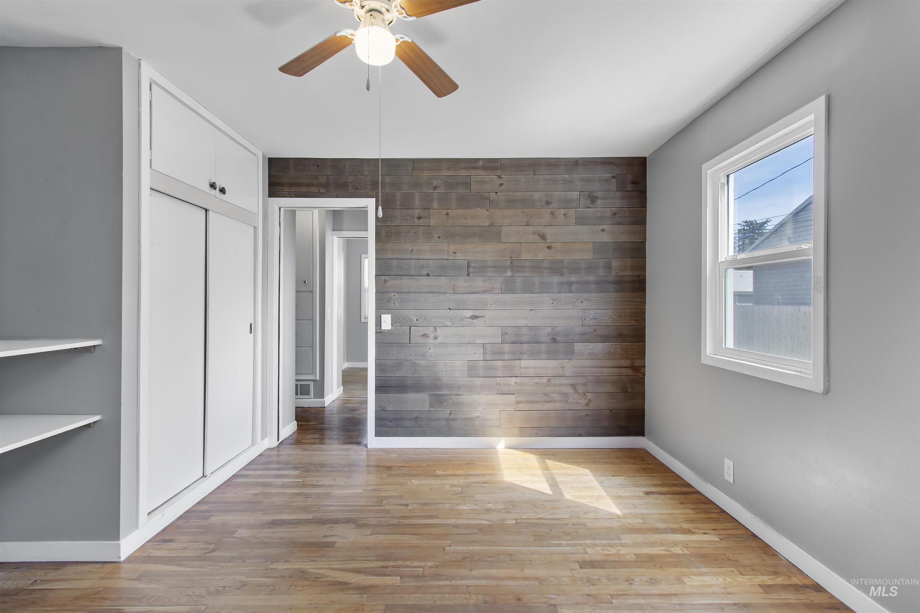 412 Madison Street Twin Falls, ID 83301 - Photo 9 of 42 Unfurnished bedroom with wood walls, light wood-style flooring, ceiling fan, and a closet