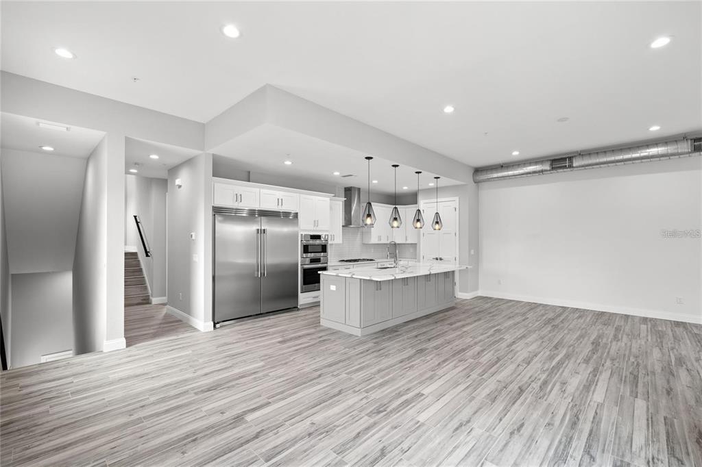 a large kitchen with a center island wooden floor stainless steel appliances and windows