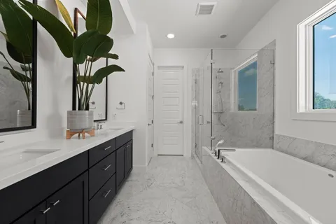 a bathroom with a double vanity sink a large mirror a bathtub and next to a window