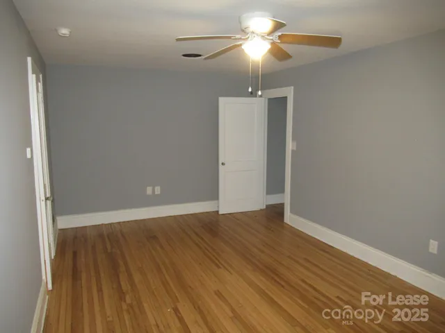 an empty room with wooden floor chandelier fan and closet area