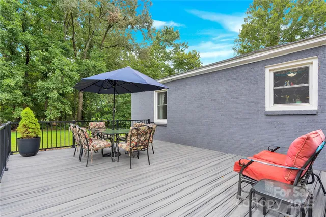 a patio with wooden floor a yard a table and chairs